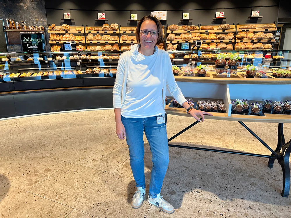 «Food Waste ist ein grosses Thema in unserer Branche»: Monika Wick, Verkaufsleiterin der Steiner-Beck AG. Eine Frau steht in einer Bäckerei. Im Hintergrund die Verkaufstheke mit vielen Broten.